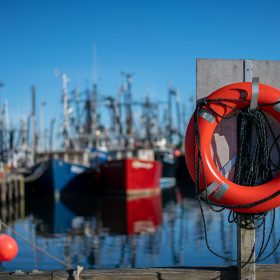 Bright orange life buoy on dock at commercial fishing harbor dock